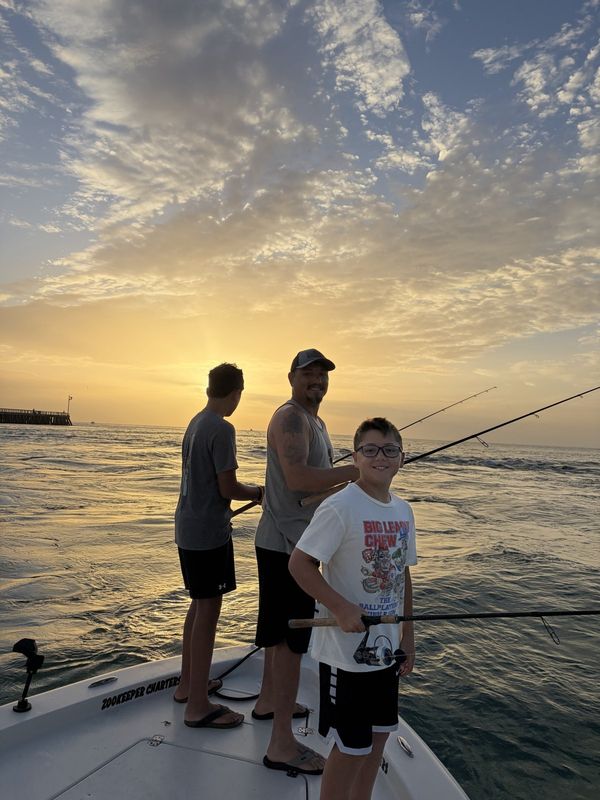 Father and son fishing from the bow at sunset