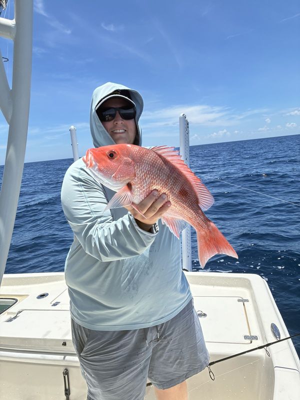 Guest with a red snapper on a calm offshore day