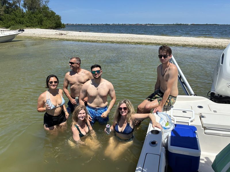 Group cooling off beside the boat on a sandbar day